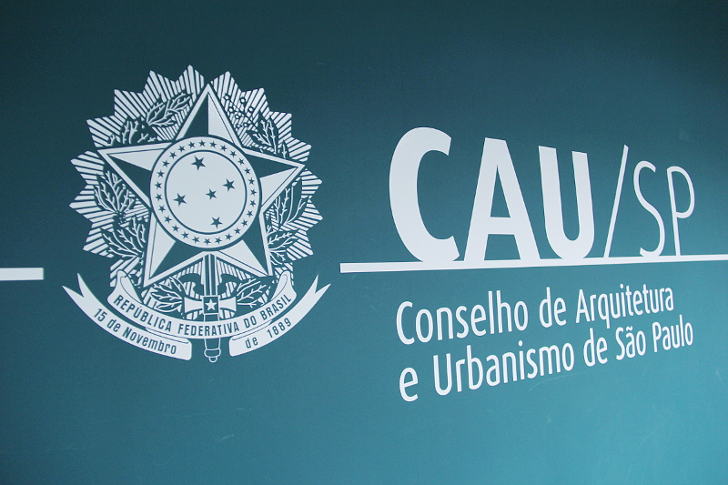 Logomarca do CAU São Paulo em uma parede verde, levemente inclinada para a direita.