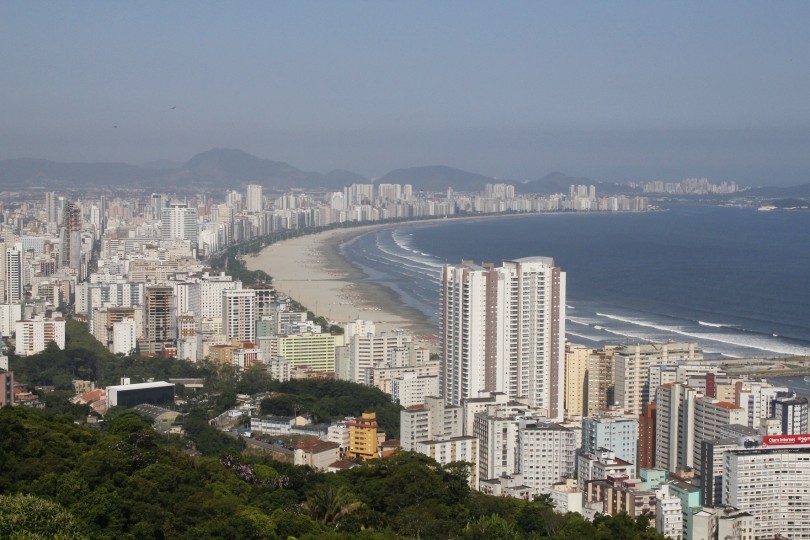 Visão aérea da cidade de Santos com prédios e mar ao fundo.