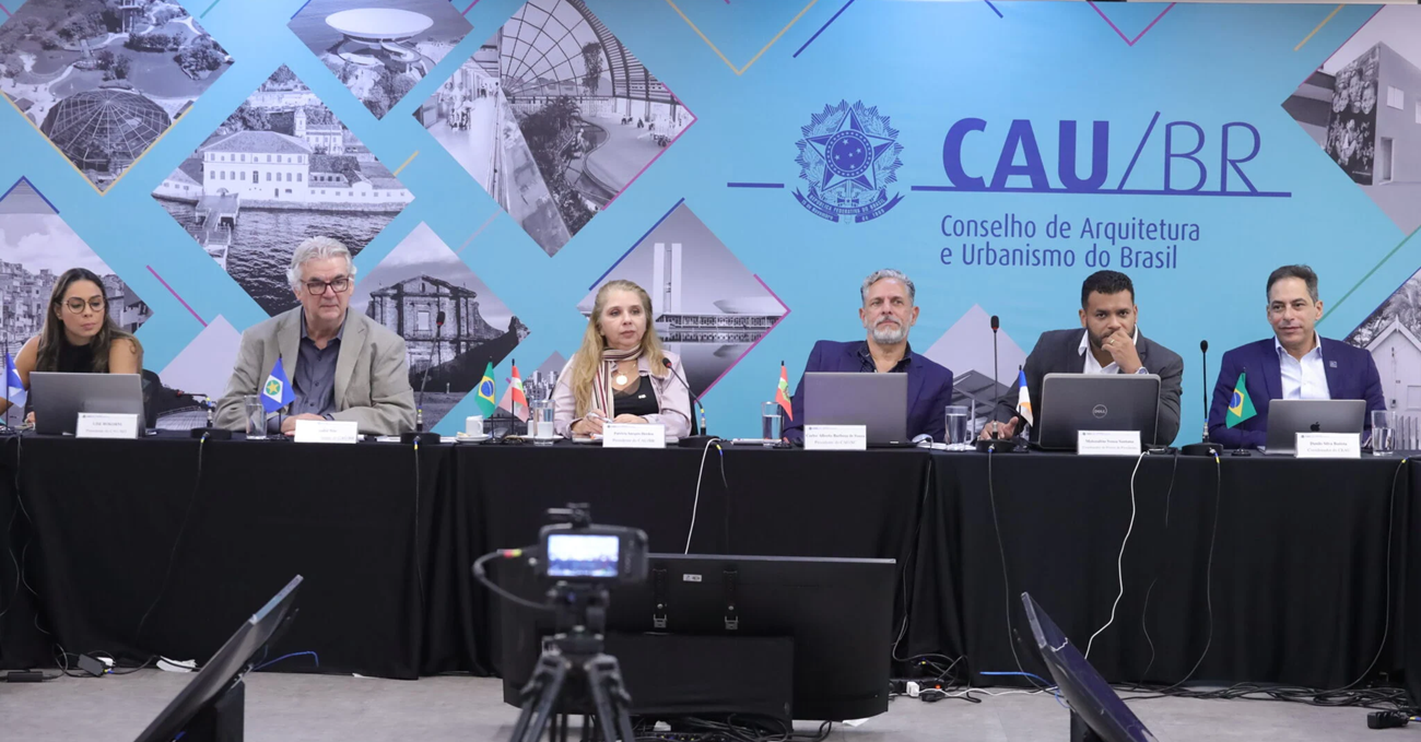 Foto mostra mesa com representantes do CAU Brasil durante reunião plenária em fevereiro .
