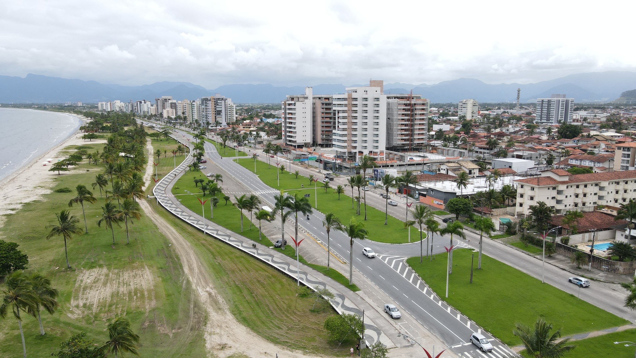 #PraCegoVerFotografia mostra avenida à beira da praia com prédios ao fundo da imagem.